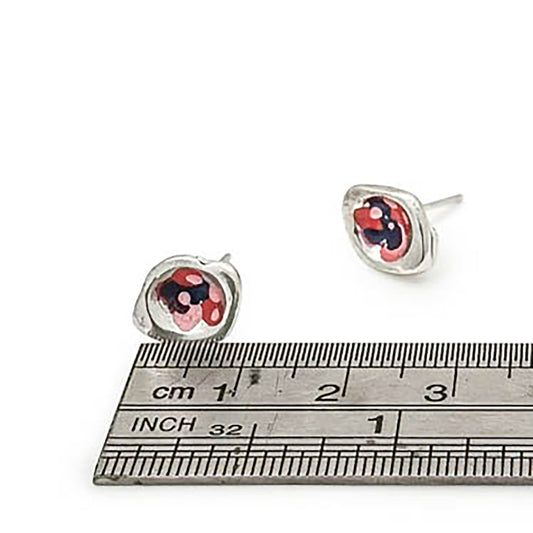 The Colour Dot Earrings in sterling silver from FR | Art Jewellery feature enchanting red ladybug designs decorated with black spots, crafted with enamel paint. Positioned against a white background, these small stud earrings add a delightful touch to any ensemble.