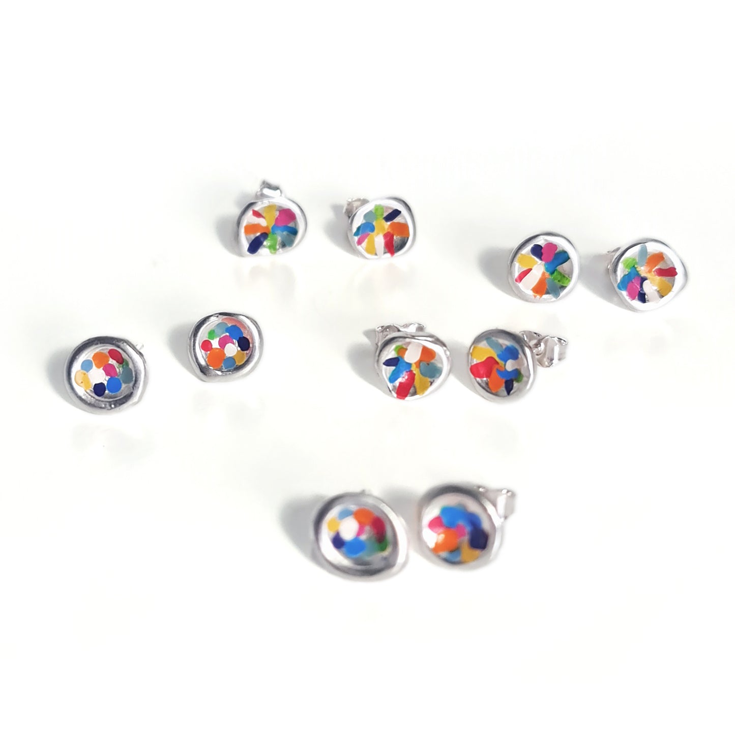 The Colour Dot Earrings Sterling Silver Forest from FR | Art Jewellery showcase two round earrings made of sterling silver, each adorned with small blue and green gemstones at their center. These earrings, known for their smooth, polished finish and contemporary design, are displayed side by side against a plain white background.