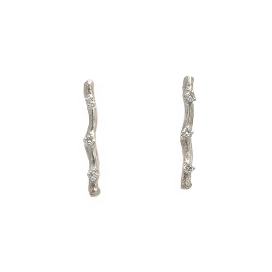 Pair of twig silver earrings with small diamond on a white background