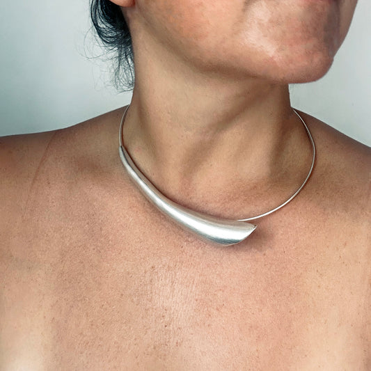 The Ebbs & Flows Necklace Sterling silver by FR | Art Jewellery is a modern handmade piece, featuring a smooth sculptural centerpiece on a simple round band, shown against a white background.
