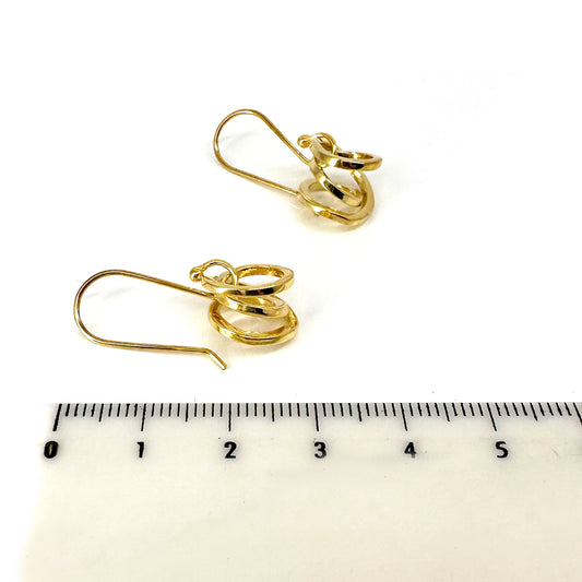 These Endless Sterling Silver Earrings from FR | Art Jewellery feature a minimalist spiral hoop design with a shiny finish, elegantly hanging from slender hooks against a white backdrop.