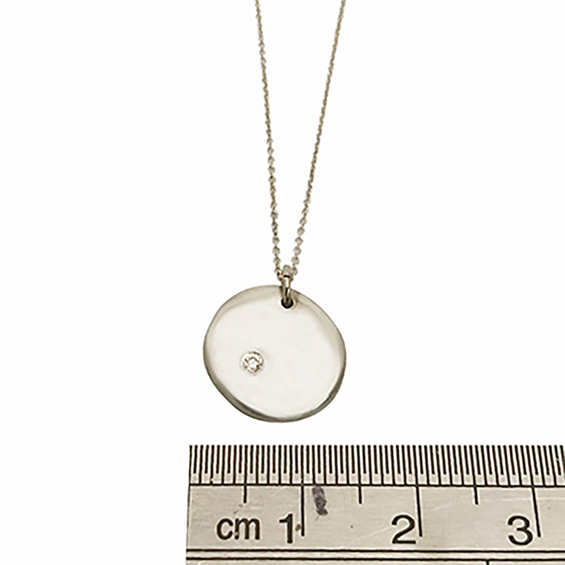 Introducing the Full Moon Sterling Silver and Gold Necklace, an exquisite piece of handmade jewelry by FR | Art Jewellery. This necklace features a round pendant with a single diamond elegantly set into its surface, gracefully hanging from a delicate gold chain against a pristine white background.