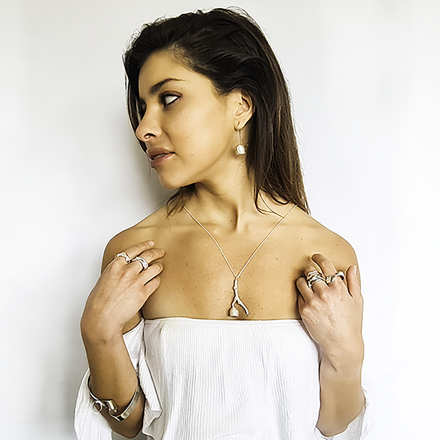 The Gum Stick Seed Necklace 55 CMS by FR | Art Jewellery is a custom-made silver pendant resembling a tree branch with an abstract shape, suspended on a delicate, thin silver chain. This handmade piece features a textured surface, adding a natural, rustic appearance to the minimalist design.