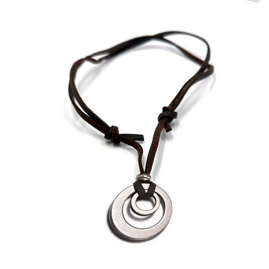 The FR | Art Jewellery Stainless Steel and Leather Circle Necklace by Thamus Design features two linked silver rings on a brown leather cord with knot and bead accents, shown against a white background.