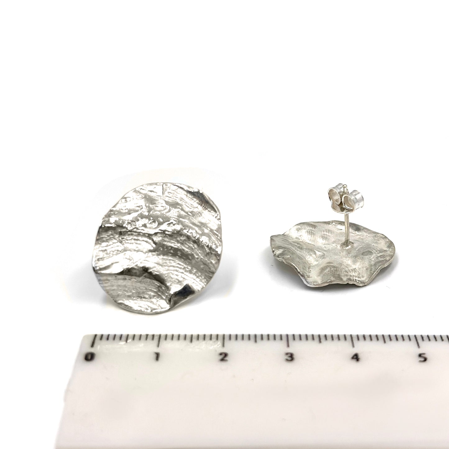 Ocean Whisper Sterling Silver Earrings by FR | Art Jewellery feature two rough, metallic silver discs with textured surfaces, capturing raw coastal beauty. From the Handmade Shell & Coastal Jewellery collection. Shown on a white background.