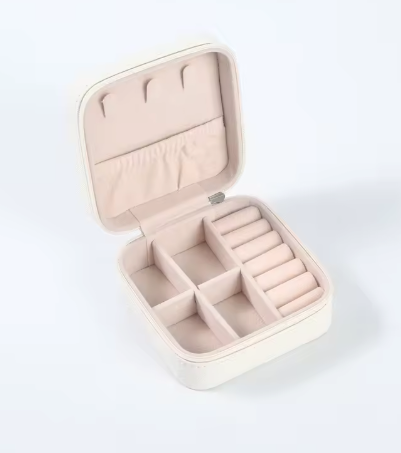 The FR | Art Jewellery Travel Jewellery storage is a small, square, cream box with a soft light pink interior, multiple compartments, ring rolls, and earring hooks—ideal for jewellery storage and shown open on a white background.