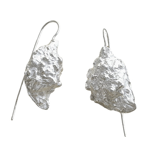 Introducing the Seeded earrings from FR | Art Jewellery: a stunning pair of silver earrings with an organic, textured design. Resembling small, rough mineral chunks, these unique pieces are attached to thin hooks for easy wearing. Ideal for enthusiasts of handmade jewellery, the metallic surface pops beautifully against any background.