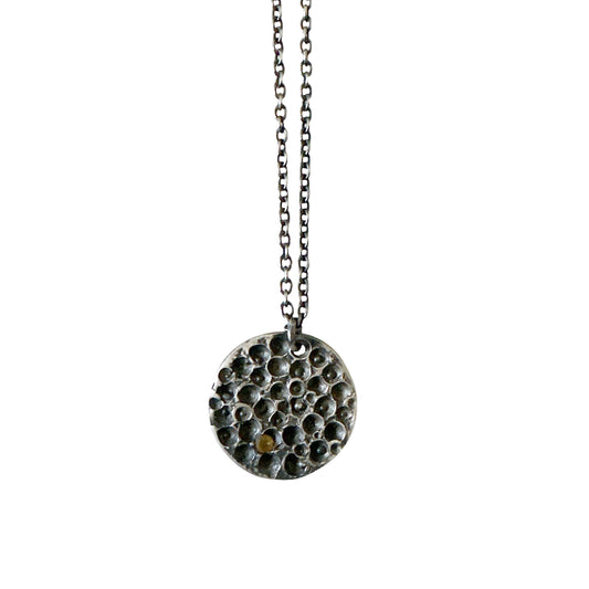 The Spot Of Light Big Sterling Silver Necklace by FR | Art Jewellery features a round, textured silver pendant with small raised bumps and a single citrine gemstone, shown on a plain white background.