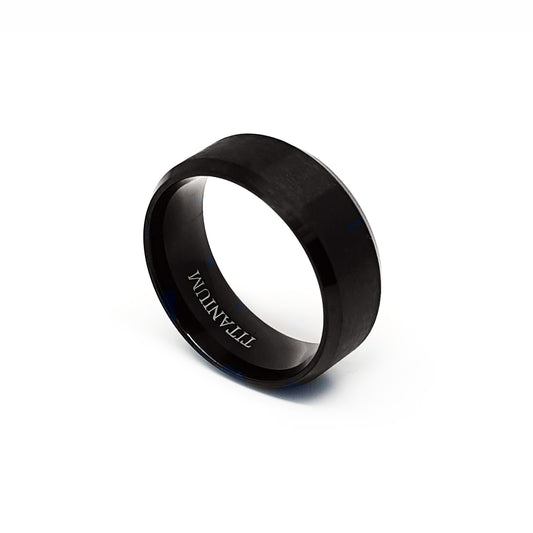The Titanium Black Bezel Ring by FR | Art Jewellery is displayed on a white background. This comfort-fit band features a smooth black matte finish and "TITANIUM" engraved on its inner surface.
