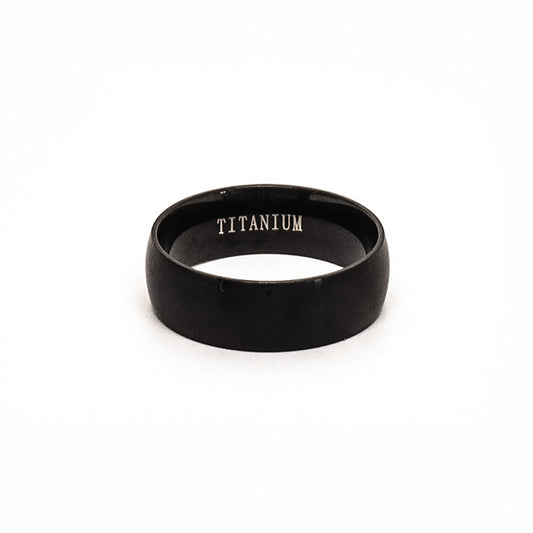 The Titanium Black Ring by FR | Art Jewellery is a comfort-fit titanium band with a black matte finish, shown upright on a white background and engraved with "TITANIUM" inside.