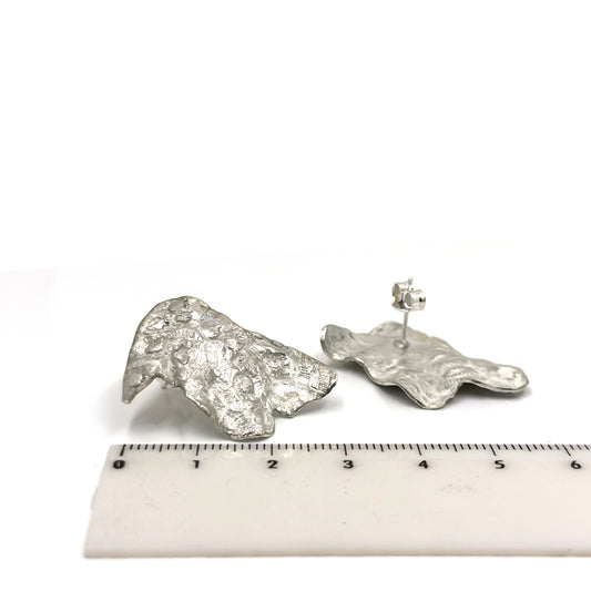 The Tidal Imprint Sterling Silver Earrings by FR | Art Jewellery feature an organic, textured design inspired by coastal forms. Handmade and part of the Bondi to Bronte Collection, they shine with a metallic finish reminiscent of tidal imprints.