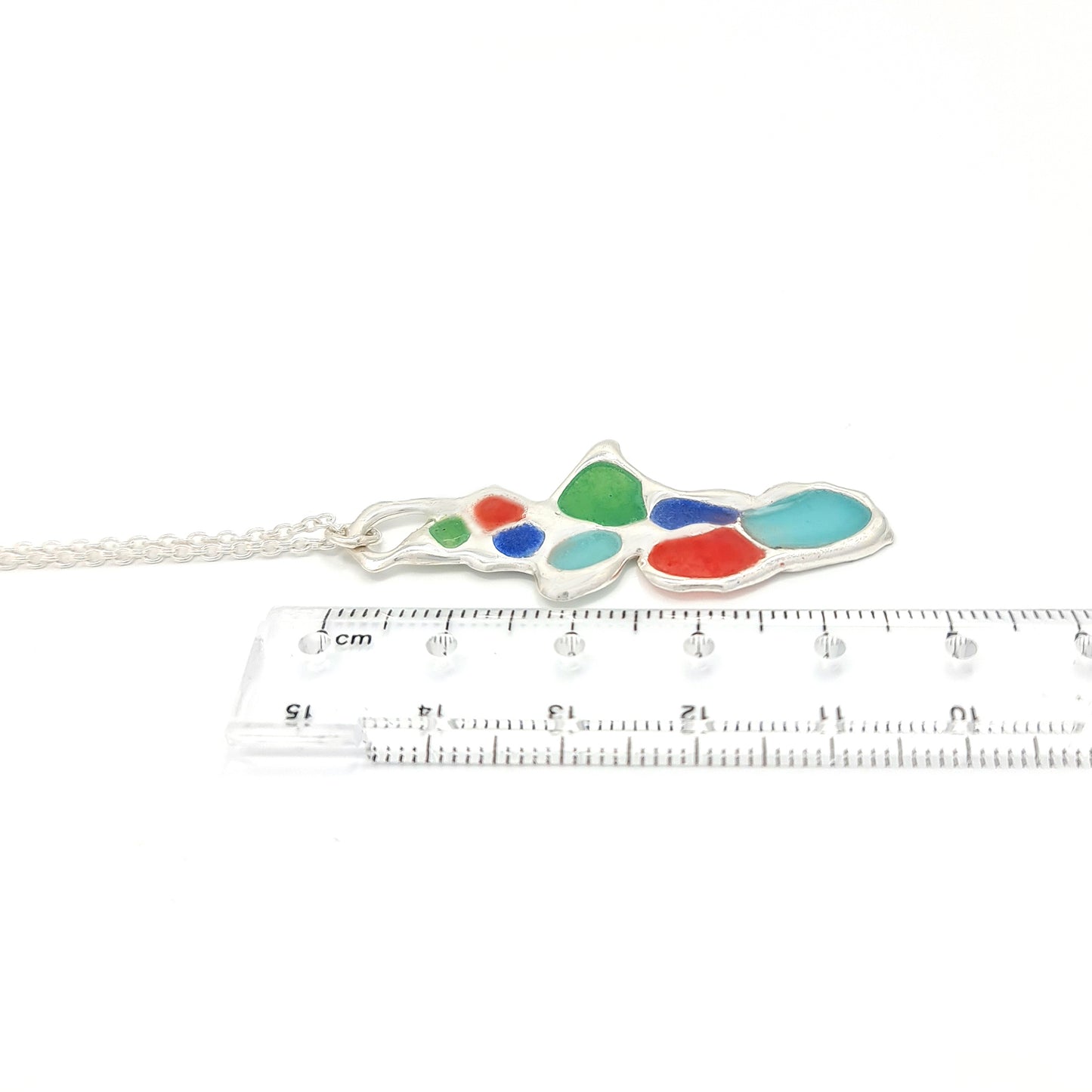 A silver chain necklace from FR | Art Jewellery, the Vitro Colours Necklace features a colorful abstract pendant with irregularly shaped sections in vibrant hues including red, green, blue, and turquoise.