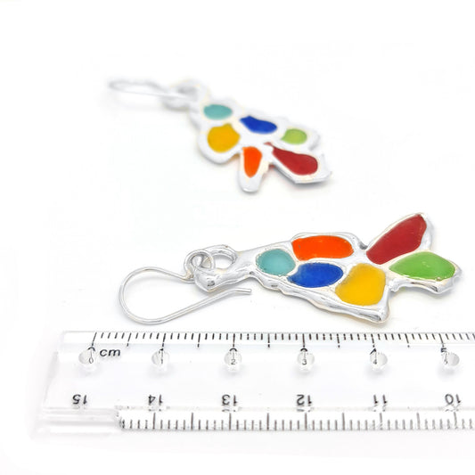 Introducing the Vitro Multicolour Earrings from FR | Art Jewellery: a stunning pair of earrings featuring a unique, abstract design with vibrant sections in red, blue, yellow, green, and turquoise, all enhanced by sterling silver. The hook-style backs ensure easy wearing and add to their elegance.