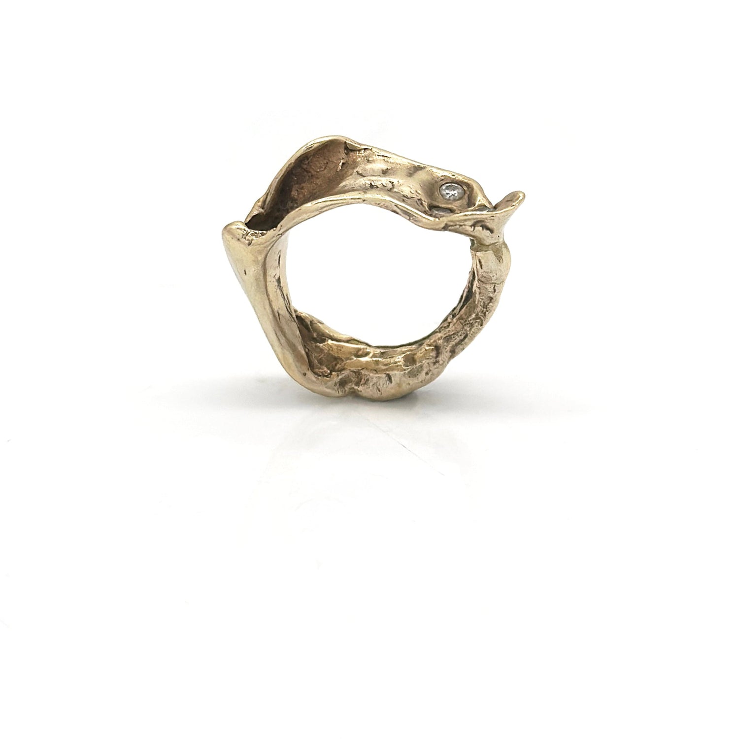 A gold ring with a unique, organic shape, featuring a serpent design. The serpent forms a loop, and a small gemstone is set in the head. The background is plain white.