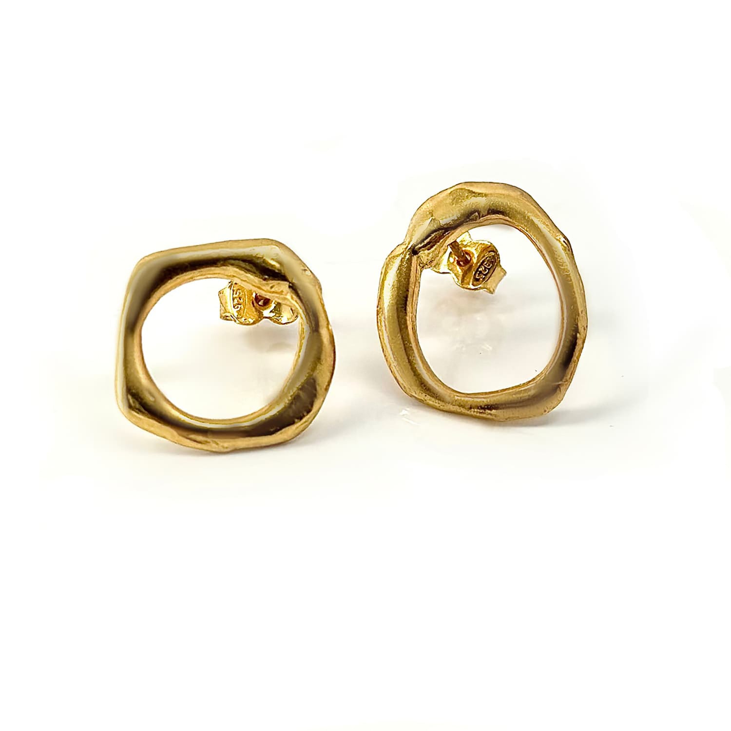 A pair of gold earrings with an open circular design and irregular edges, featuring butterfly backings on a white background.