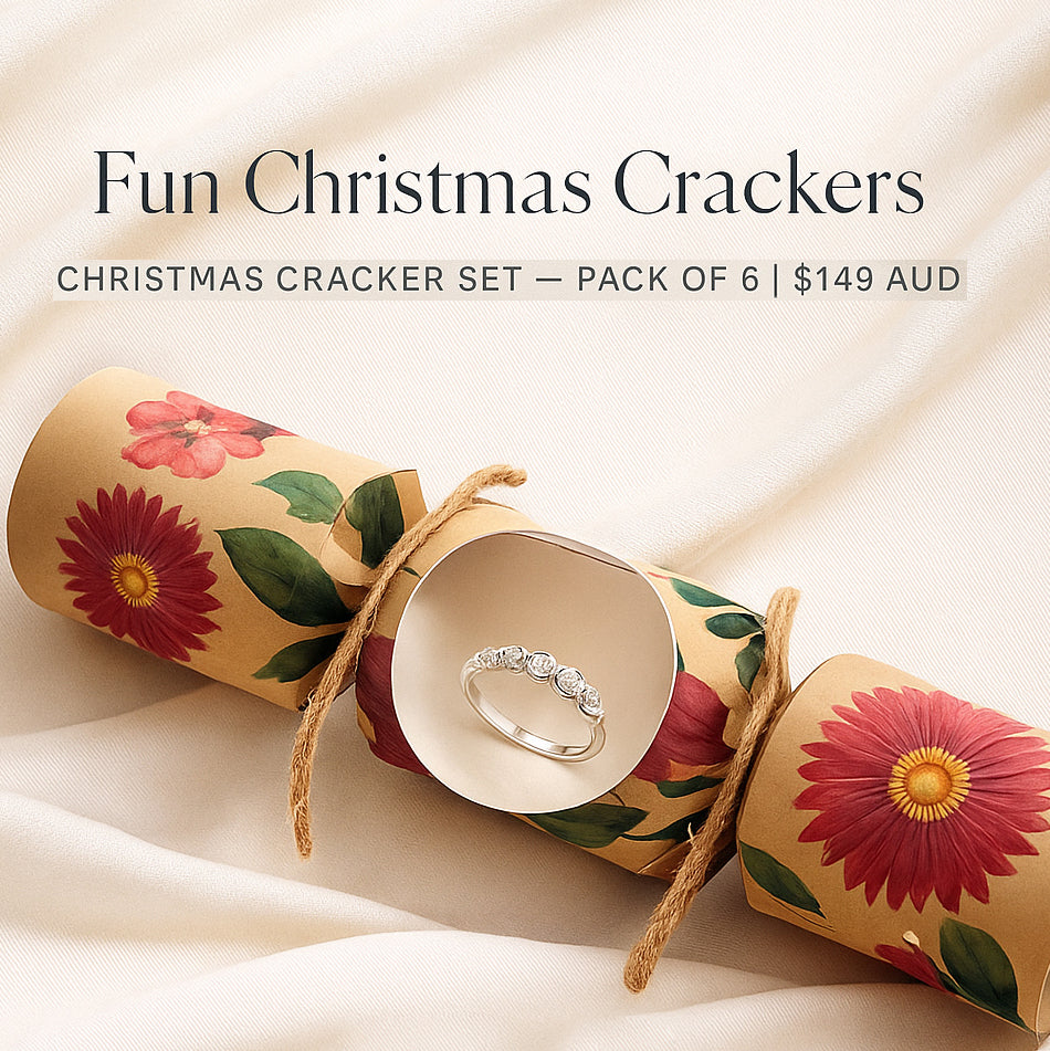 A floral Christmas cracker set with a ring inside is displayed on a soft cream fabric. Text reads: "Fun Christmas Crackers, pack of 6, $149 AUD.