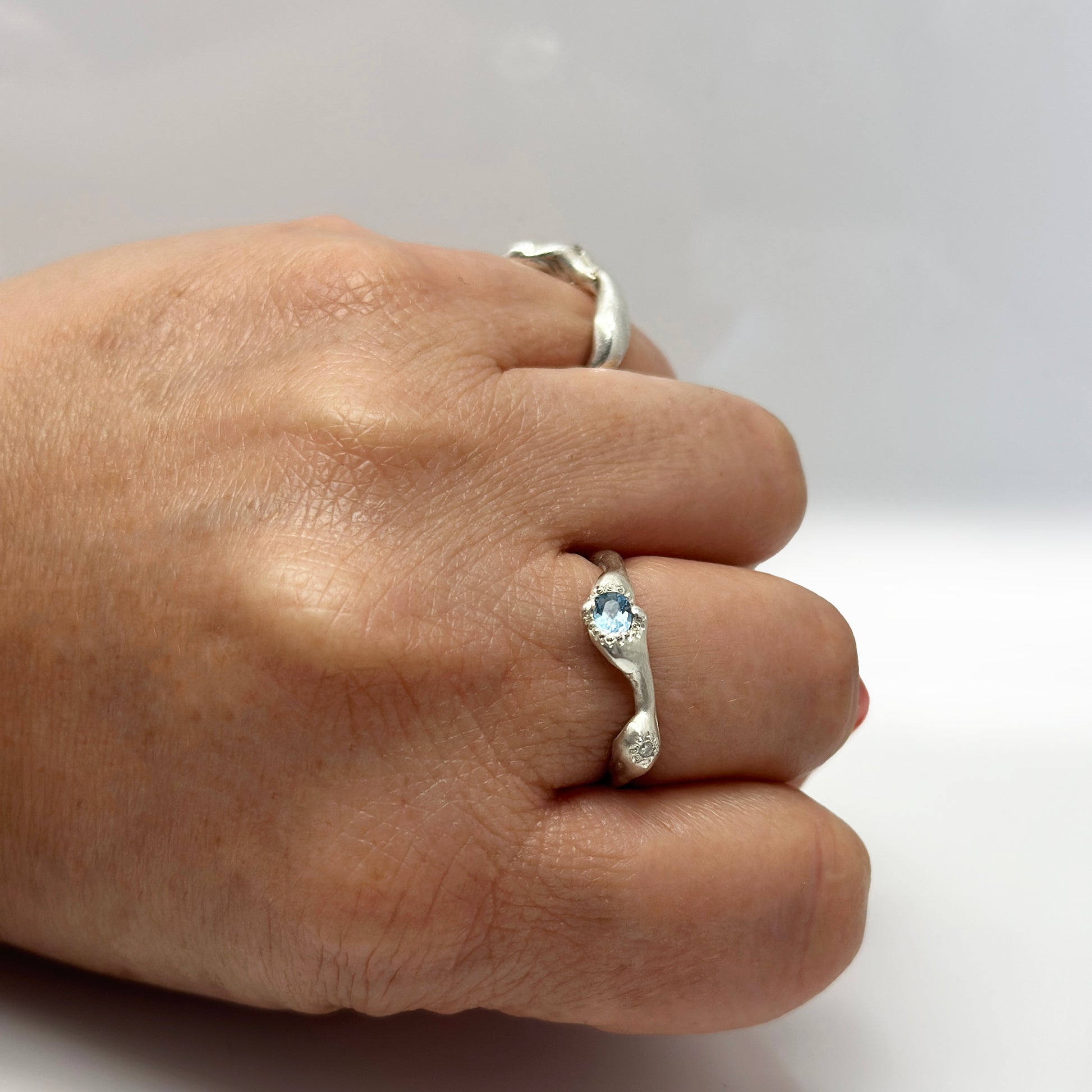 The Aquamarine and Diamond Ring by FR | Art Jewellery is a handmade sterling silver ring from Sydney, featuring a wavy organic band and a central blue gemstone, shown against a plain white background.