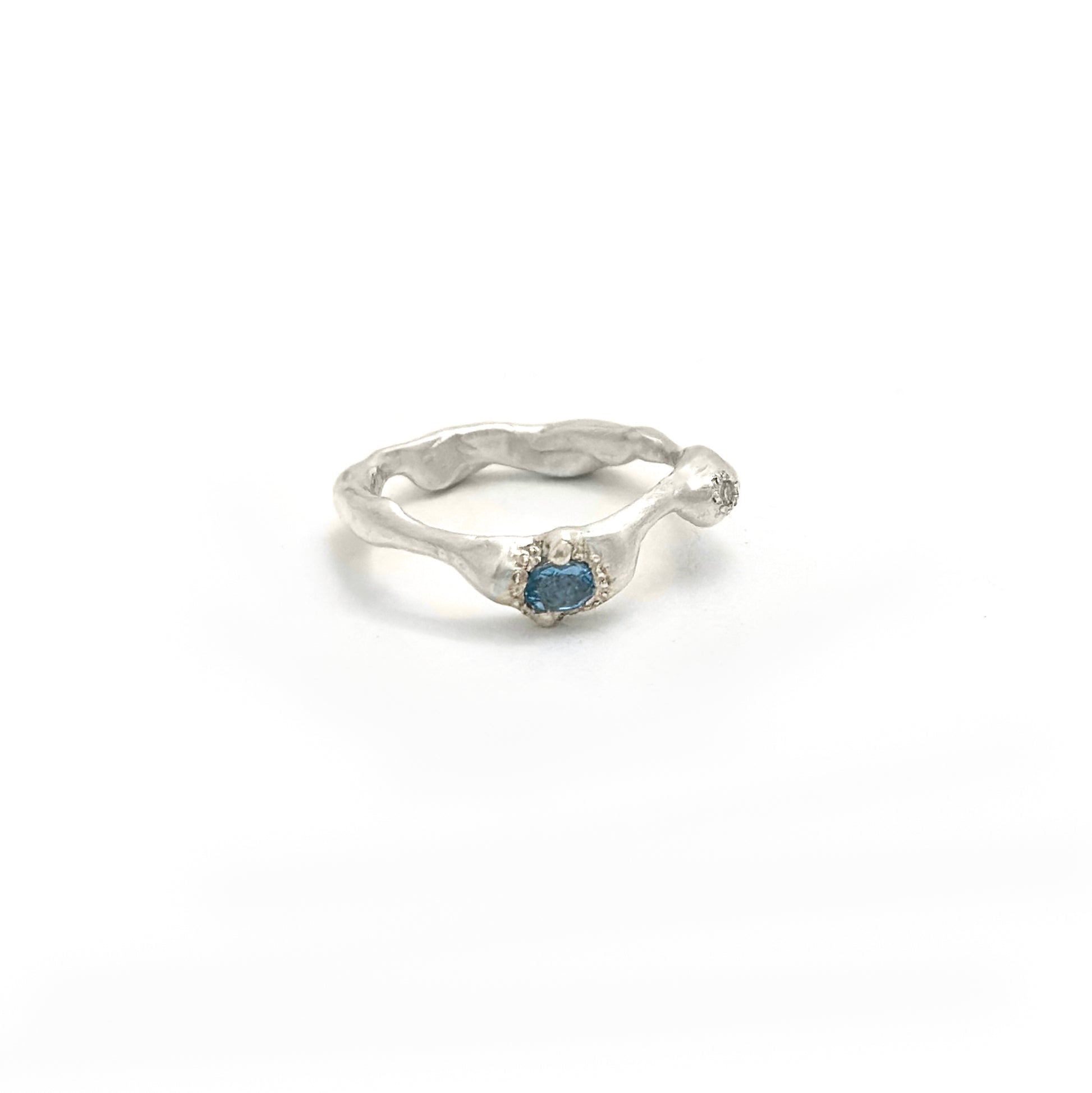 The Aquamarine and Diamond Ring by FR | Art Jewellery is a handmade sterling silver ring from Sydney, featuring a wavy organic band and a central blue gemstone, shown against a plain white background.