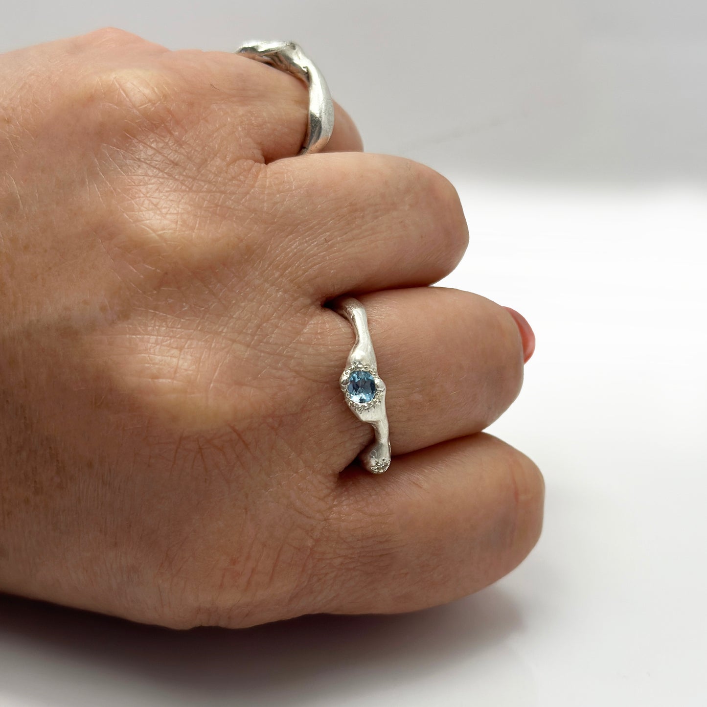 The Aquamarine and Diamond Ring by FR | Art Jewellery is a handmade sterling silver ring from Sydney, featuring a wavy organic band and a central blue gemstone, shown against a plain white background.