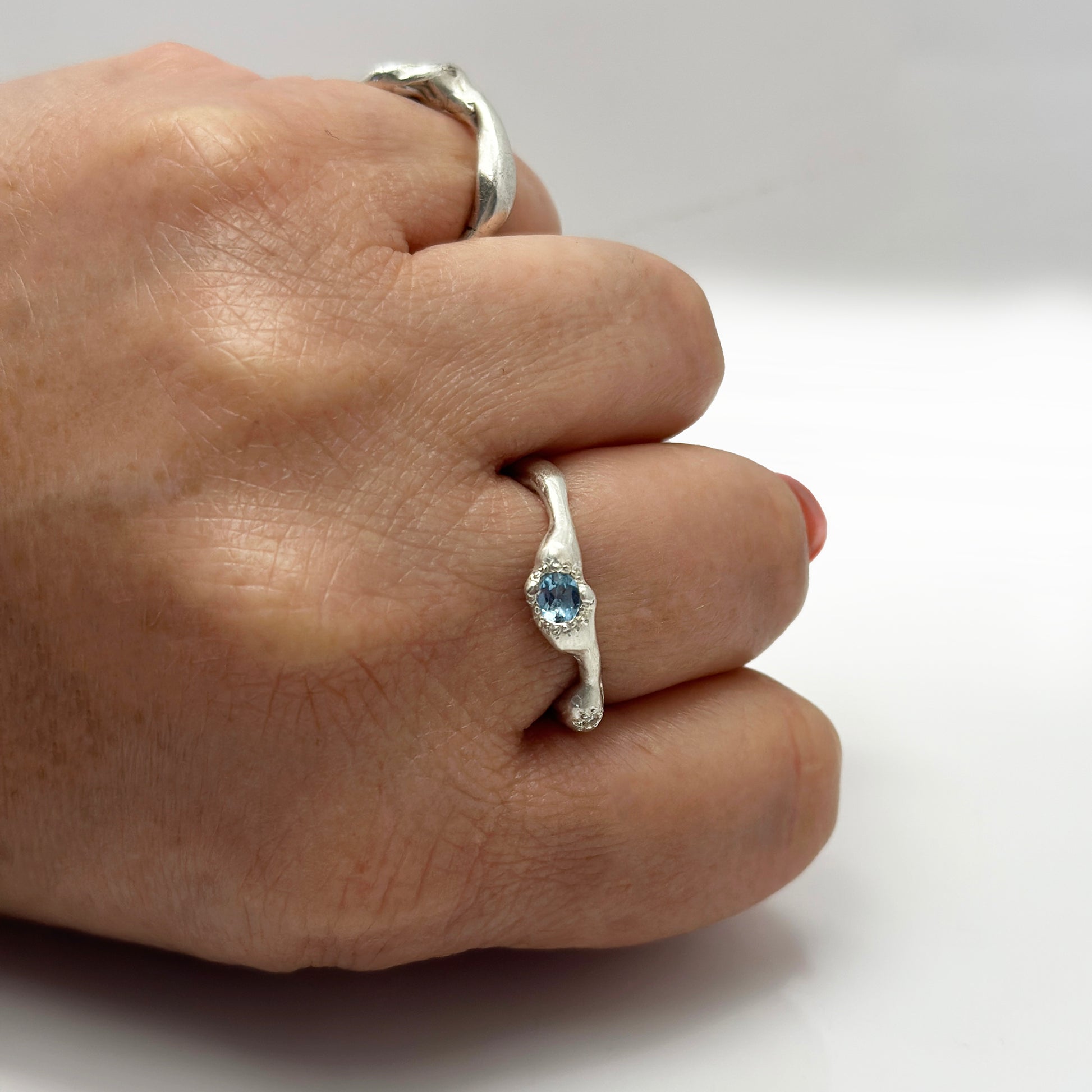 The Aquamarine and Diamond Ring by FR | Art Jewellery is a handmade sterling silver ring from Sydney, featuring a wavy organic band and a central blue gemstone, shown against a plain white background.