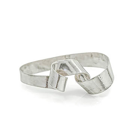 The Archi Bangle by FR | Art Jewellery, a minimalist silver piece, features a unique twisted loop design and lies on a white background. This handmade accessory boasts a reflective, polished finish, with the twisted loop lending an elegant and modern aesthetic.