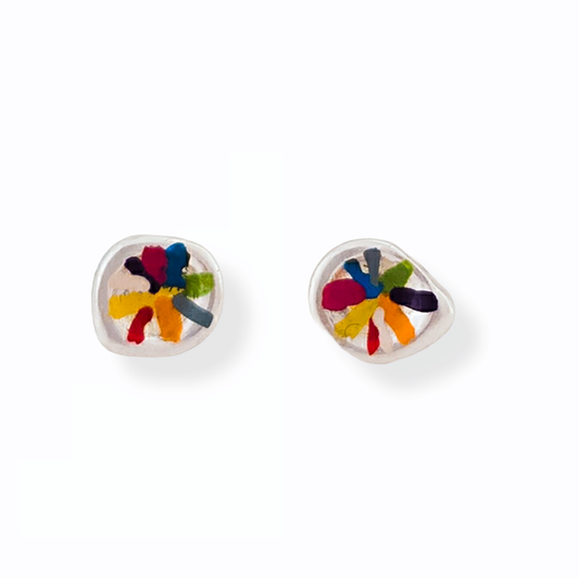 A pair of Colour Dot Earrings Colourlines by FR | Art Jewellery on a white background. One earring is positioned to showcase the front, featuring an intricate design with red, blue, green, and yellow colors. The other earring is laid on its back, revealing the silver post and butterfly clasp.