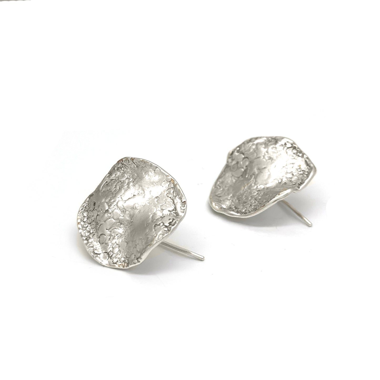 Introducing the Coral Earrings from FR | Art Jewellery's Bondi to Bronte Collection. These silver textured stud earrings feature unique, organic shapes with a hammered, uneven surface, providing a rustic, handcrafted appearance. They have simple posts designed for pierced ears and are set against a plain white background.