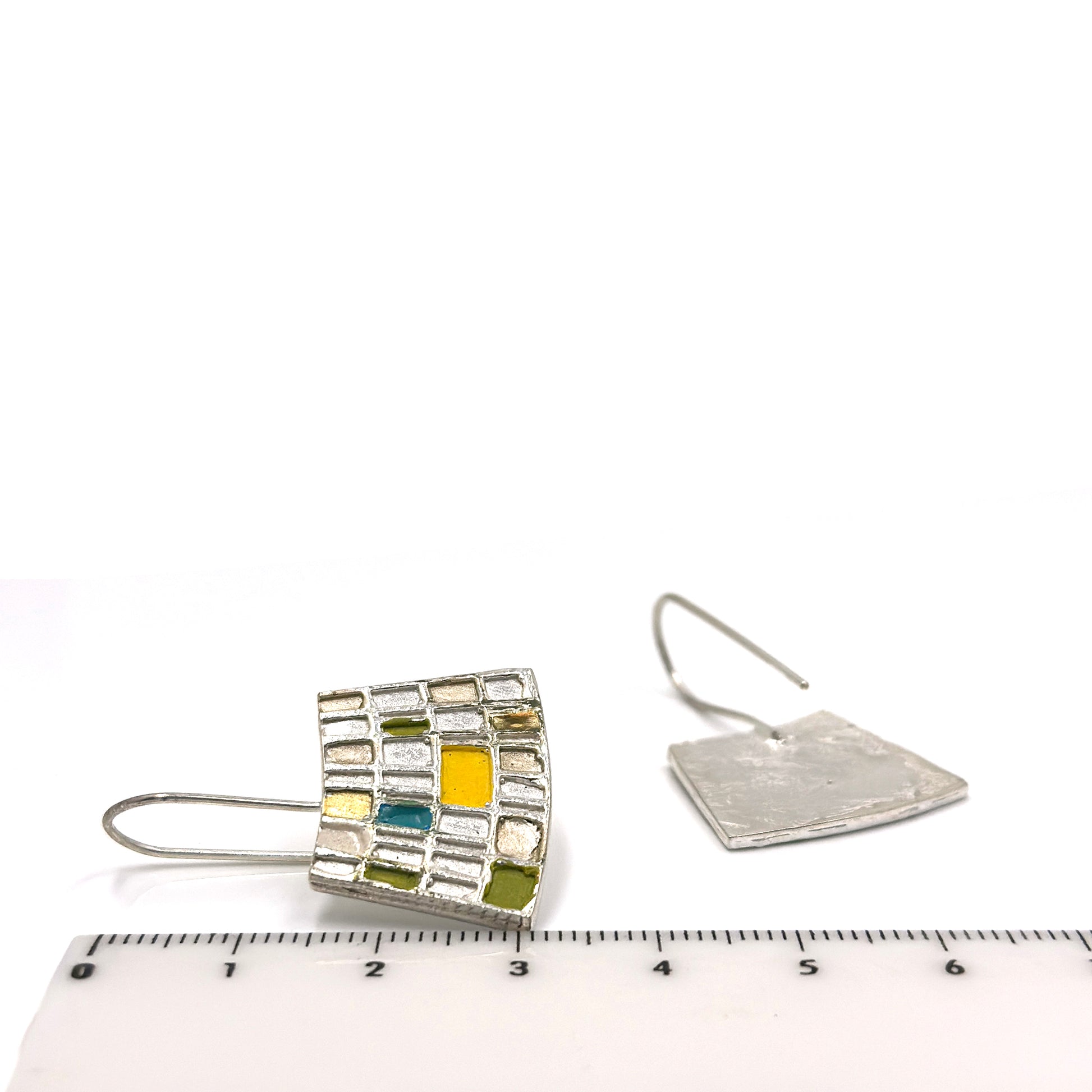 Introducing the Curve Klimty Earrings by FR | Art Jewellery, a stunning pair of gold-plated silver earrings featuring a square mosaic design. The squares are beautifully filled with an array of colors, including yellow, green, and blue. These handmade pieces showcase a modern, geometric style and hang elegantly from simple hooks. Custom-made orders are available upon request.