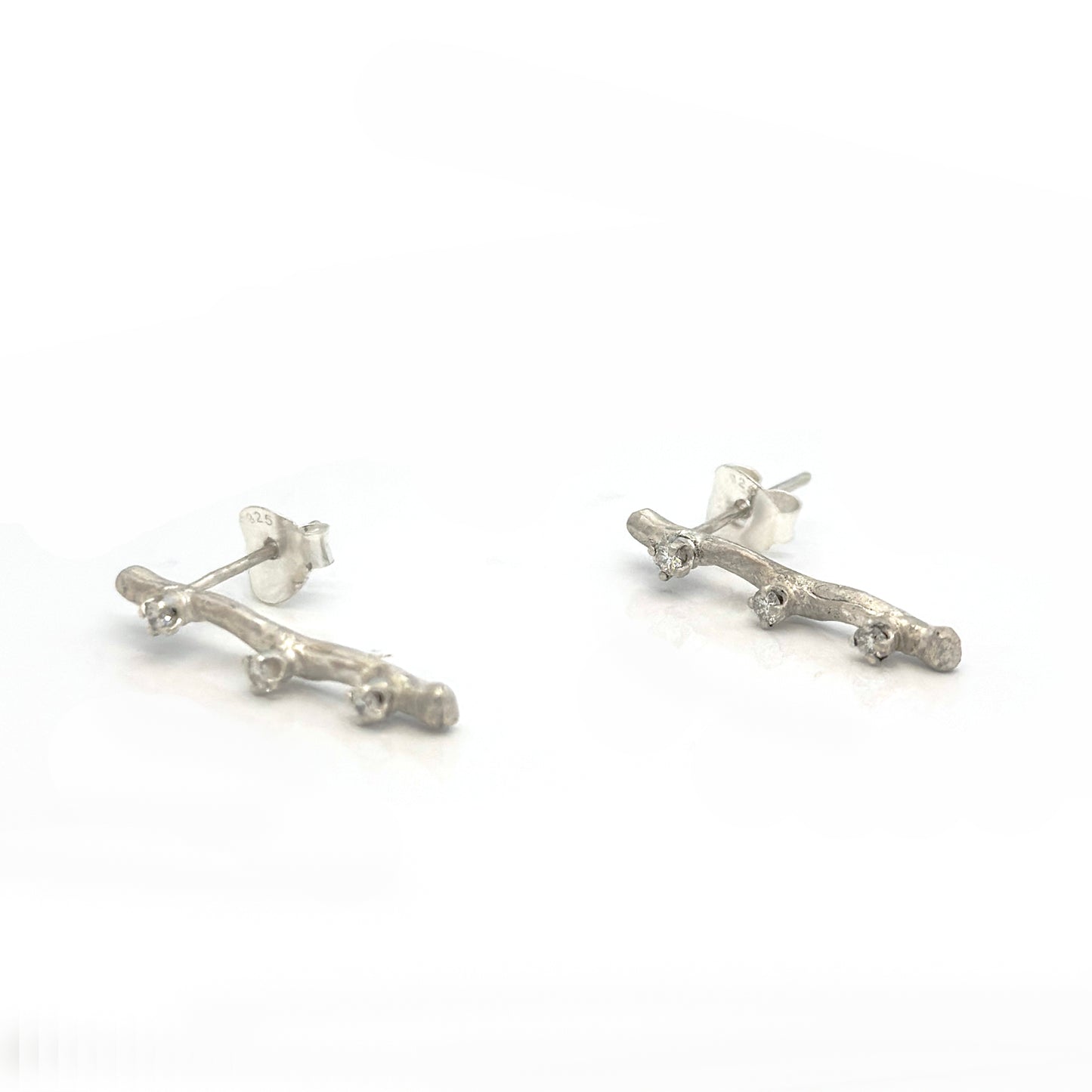 Silver branch-like earrings on a white background