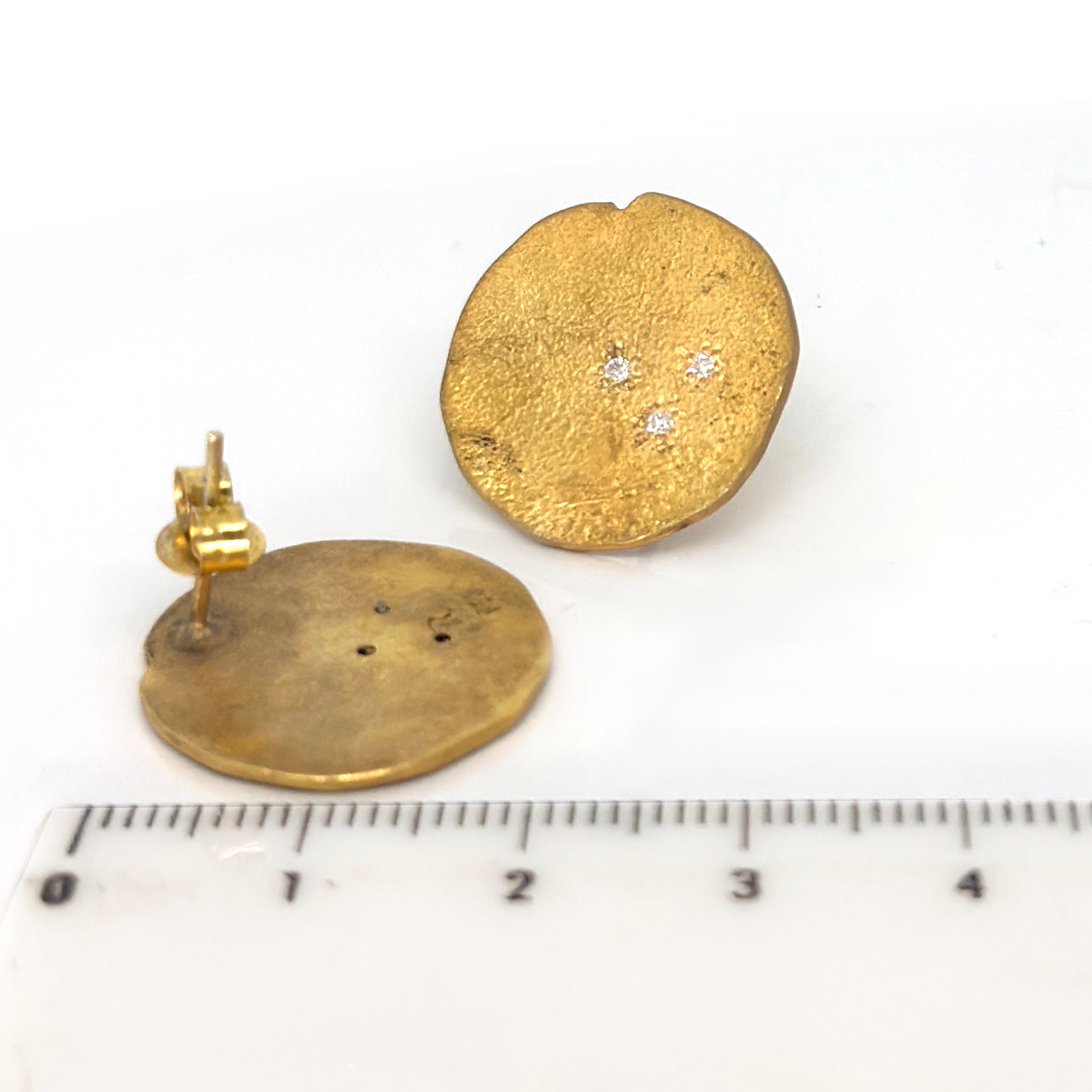 The FR | Art Jewellery Ebb & Flow Round Earrings Medium are gold-plated silver diamond studs, each hand-textured and adorned with three sparkling diamonds in a triangular design, shown on a white background.