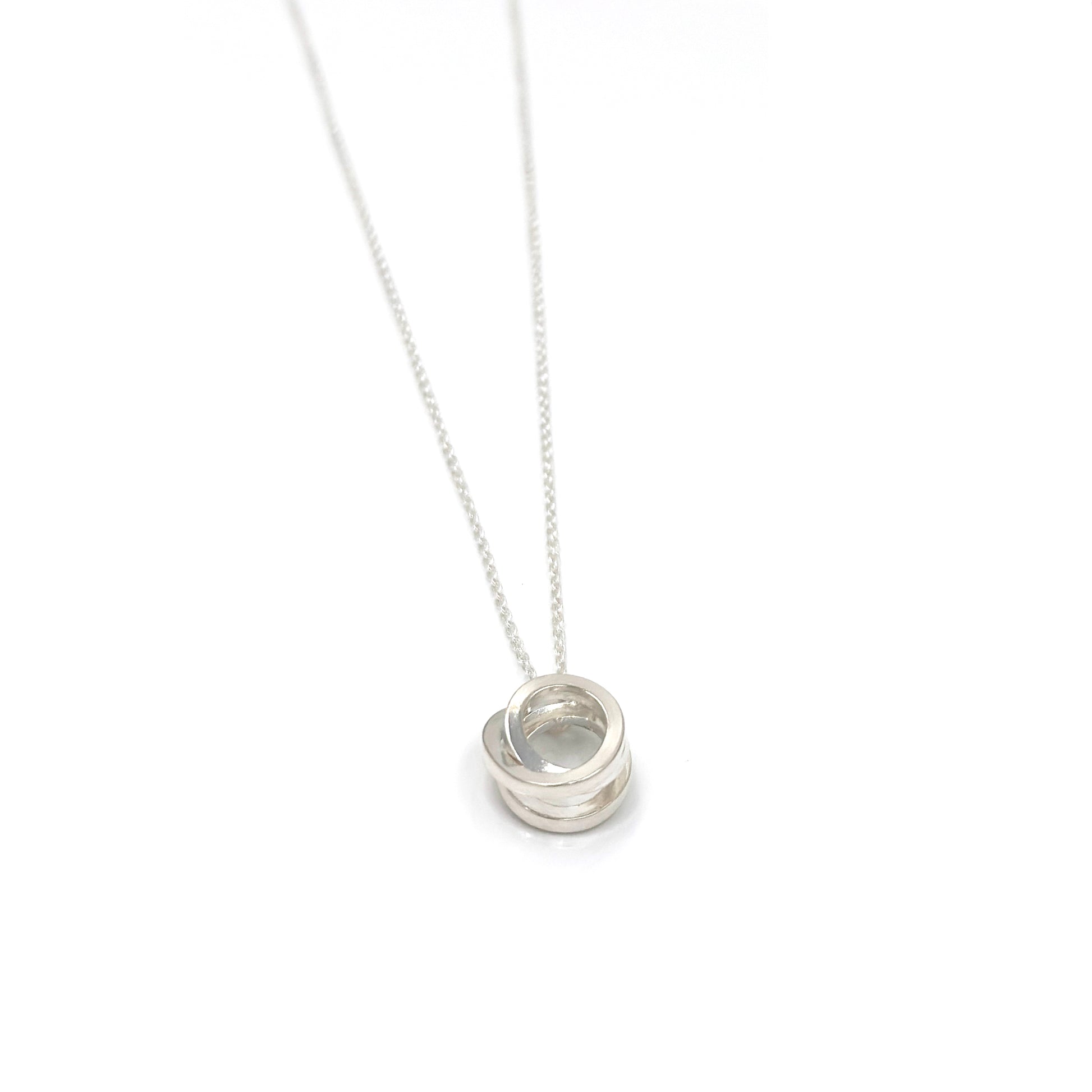 Introducing the Endless Necklace by FR | Art Jewellery: a stunning silver necklace showcasing a delicate chain and a pendant of intricately interlocking circles. The circles are smoothly polished, embodying an elegant and timeless design. The simplicity of the chain accentuates the intricate pattern of the pendant, perfectly representing our commitment to exquisite handmade jewellery.