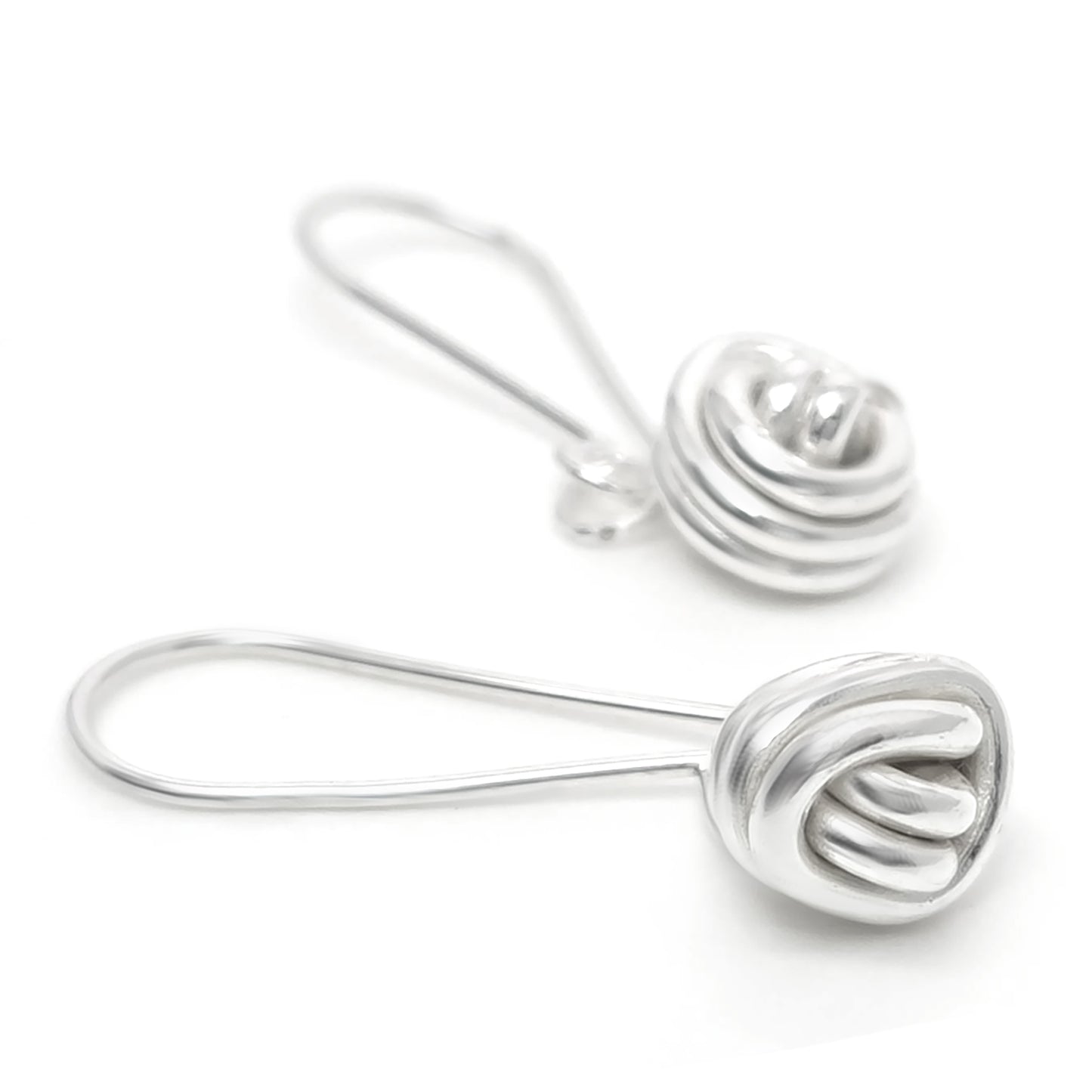 A pair of Endlessly Earrings by FR | Art Jewellery is displayed against a white background. Each handmade silver earring features a hook design with an intricately twisted, knot-like detail at the end. These modern and elegant earrings are perfect for custom-made orders.