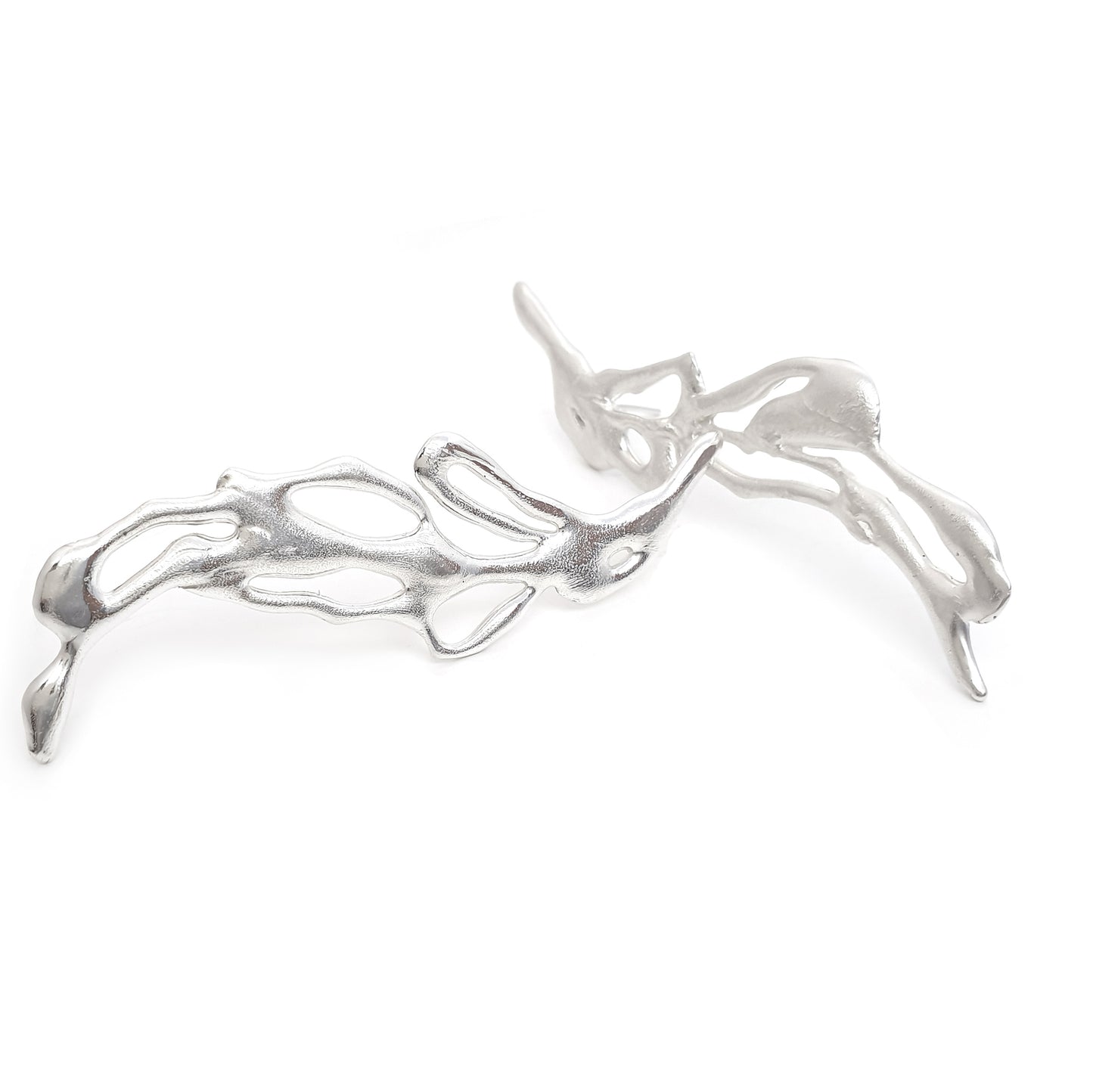 The Flow Earrings by FR | Art Jewellery are a pair of silver abstract earrings featuring an intricate, flowing design that resembles delicate intertwined branches or leaves. They appear lightweight and are artistically crafted with smooth, polished surfaces—a true testament to the elegance of handmade jewellery.