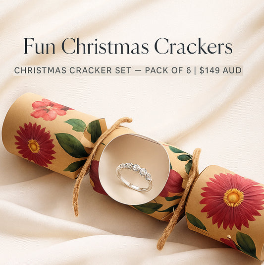 A Handcrafted Christmas Cracker by FR | Art Jewellery with a sterling silver ring is displayed on beige fabric. Text above: “Handcrafted Christmas Crackers Designed to Delight — Set of 6 | $149 AUD.” Celebrate festive surprises!.