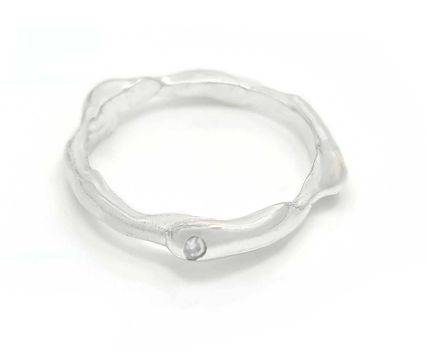 A close-up of the Freedom Diamond ring by FR | Art Jewellery showcases its sterling silver band with a wavy, irregular design. The unique craftsmanship is emphasized by a small, round, clear gemstone set on its surface. The inner side of the band is stamped with "925," confirming its quality as sterling silver.