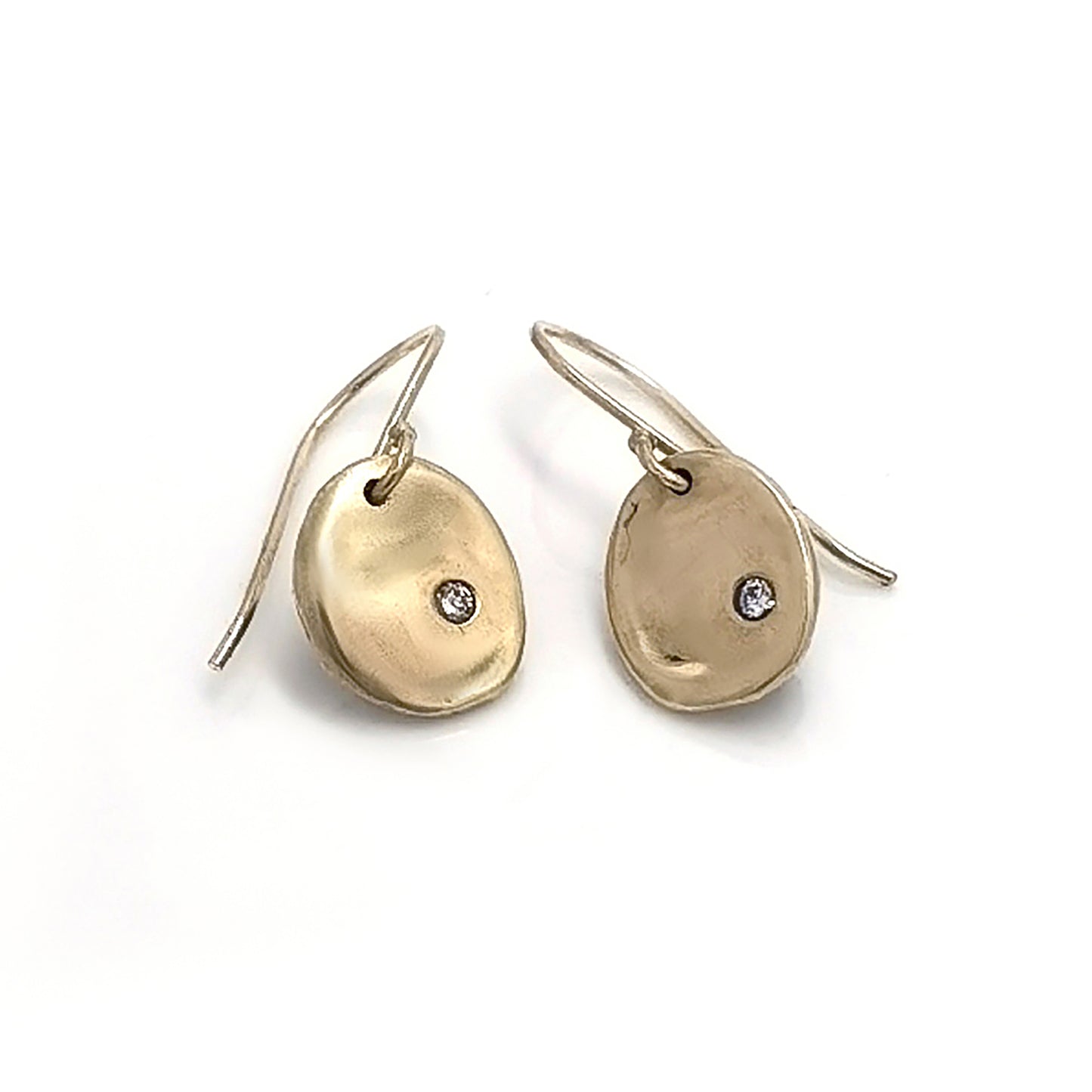 A pair of elegant Full Moon Earrings by FR | Art Jewellery, each featuring a small, round diamond set in the center. The gold discs have a slightly irregular, organic shape, giving them a unique and artisanal appearance. These handmade jewellery pieces are attached to slim hooks for wearing.