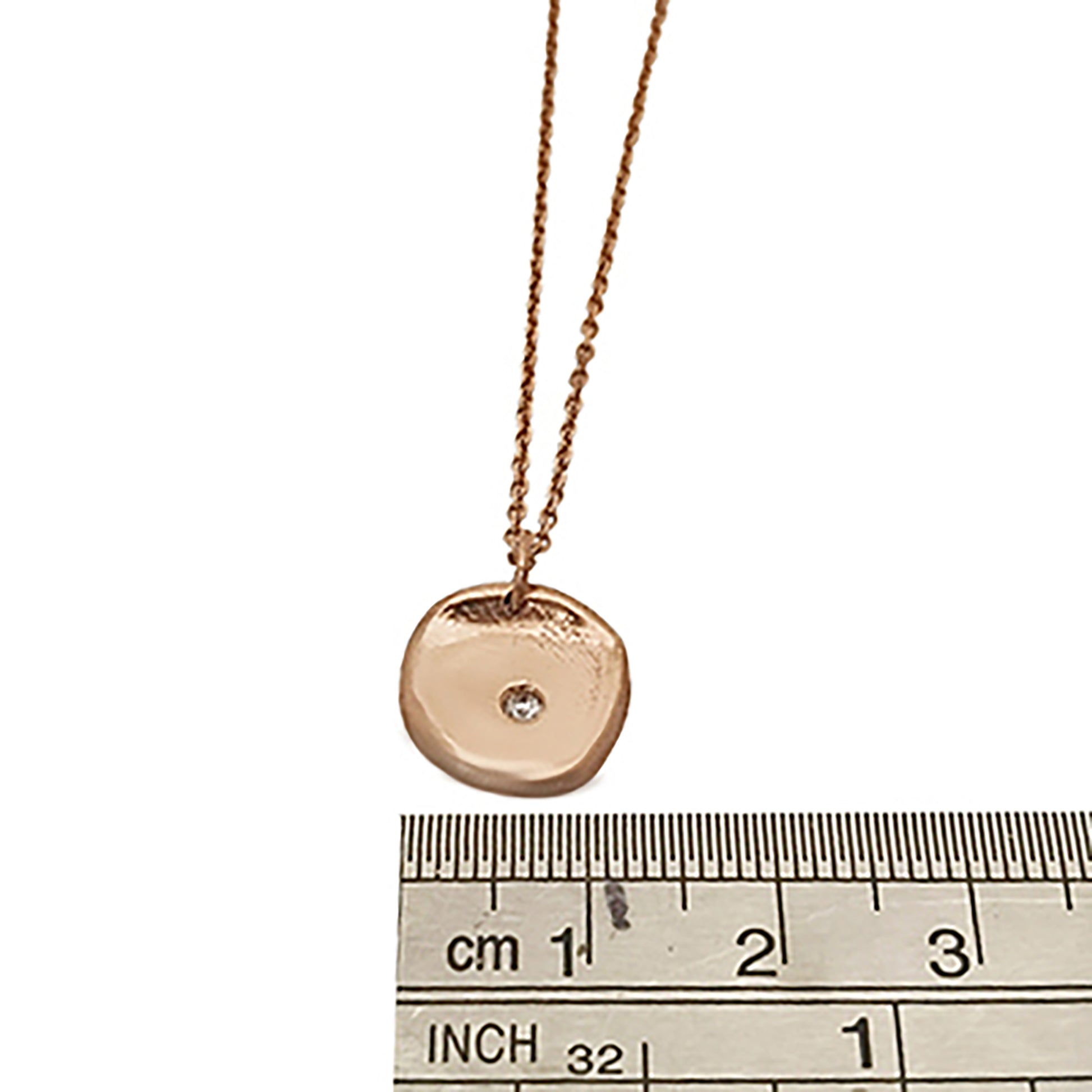 The Full Moon Necklace by FR | Art Jewellery is a delicate gold piece that features a round pendant with a small diamond embedded in the center. The thin chain perfectly complements the simple yet elegant design of the pendant, which boasts a smooth, slightly irregular surface. This necklace exemplifies the craftsmanship of handmade jewellery.