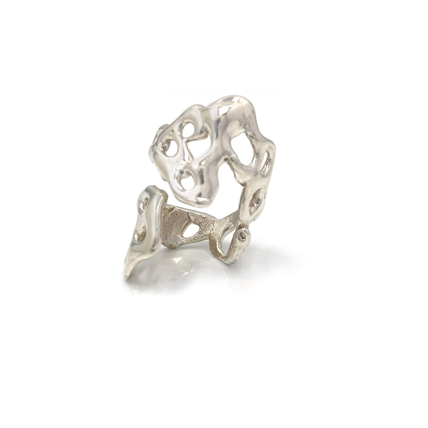 A close-up image of the Climber Ring by FR | Art Jewellery showcases its intricate, abstract design with multiple openings. The ring features an organic, flowing structure and a polished finish that lends it a modern, artistic appearance. This piece of handcrafted jewellery is also available in gold plating for custom-made orders.


