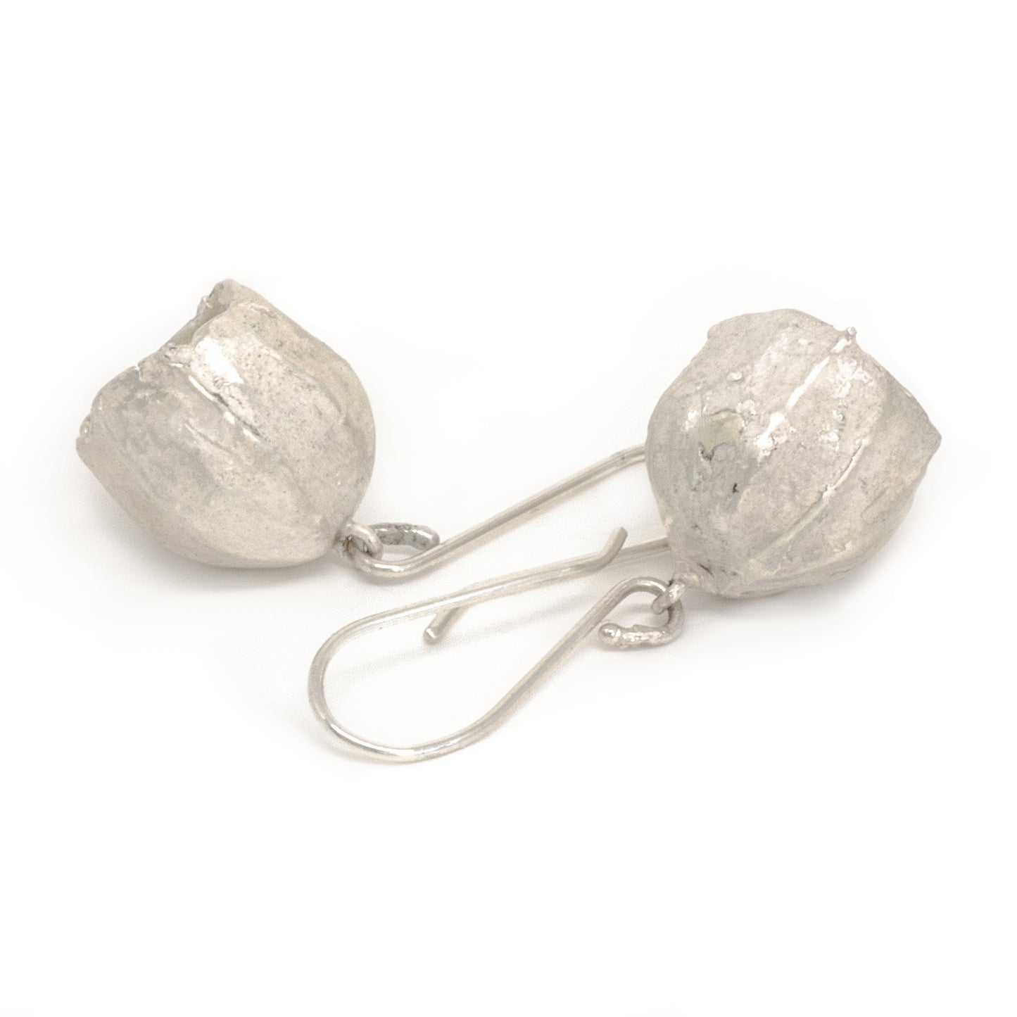 Close-up of a pair of FR | Art Jewellery's Gum Seeds Earrings. Each earring showcases a silver, rounded, slightly crumpled textured bulb dangling from a delicate hook. The earrings are laid out on a white background with the hooks intersecting. These elegant pieces are part of our handmade jewellery collection, perfect for custom-made orders.