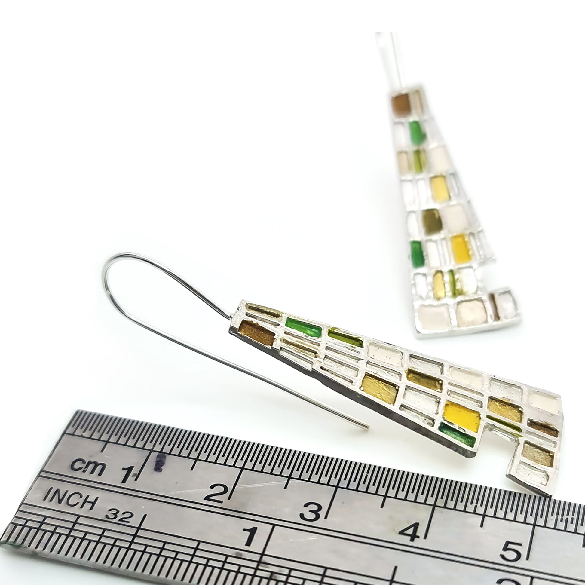 Introducing the Gustav Small Earrings by FR | Art Jewellery: A pair of handmade, dangling earrings showcasing a mosaic design with tiny squares and rectangles in a vibrant array of blue, green, purple, and beige. These silver-set earrings offer a geometric and modern aesthetic, making them perfect for custom-made orders.