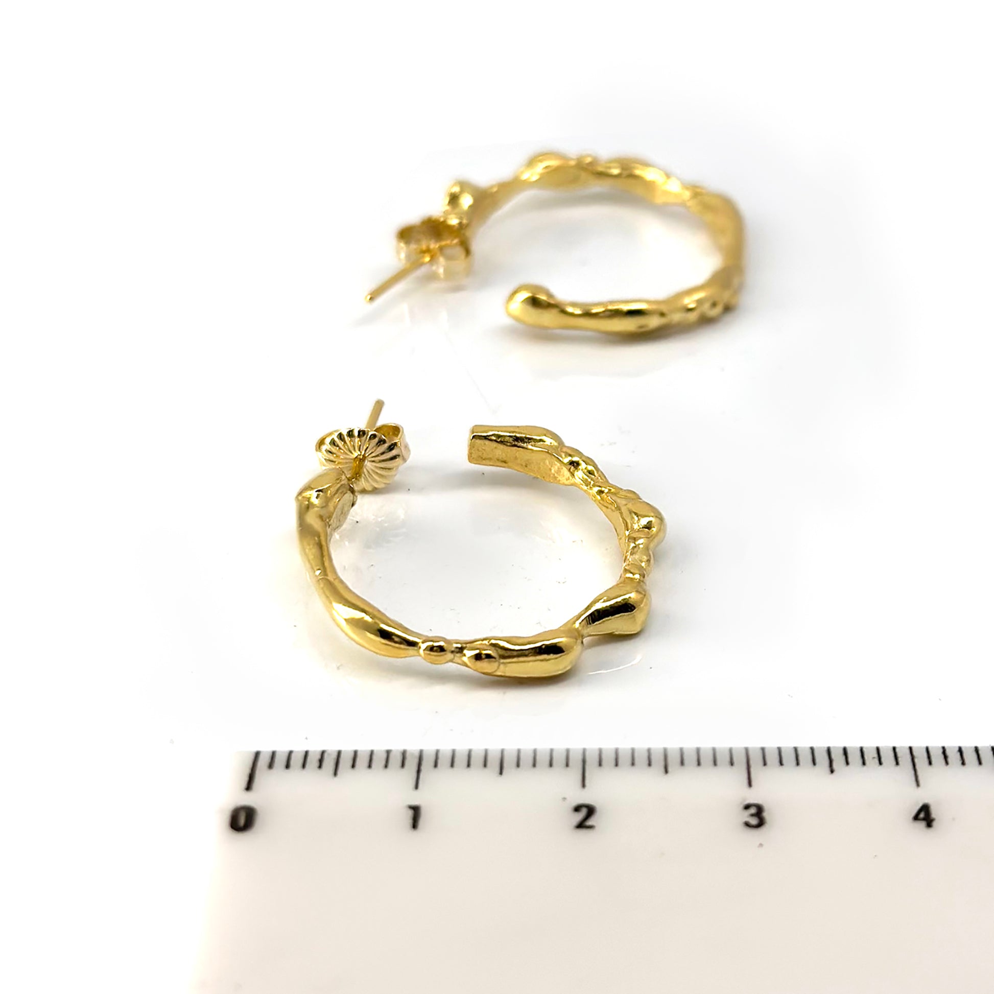 A pair of small, irregularly shaped Hoop 25mm earrings made of sterling silver with a textured, organic design by FR | Art Jewellery. Each earring features a post and butterfly clasp closure and is part of the Curves Collection, displayed against a plain white background.