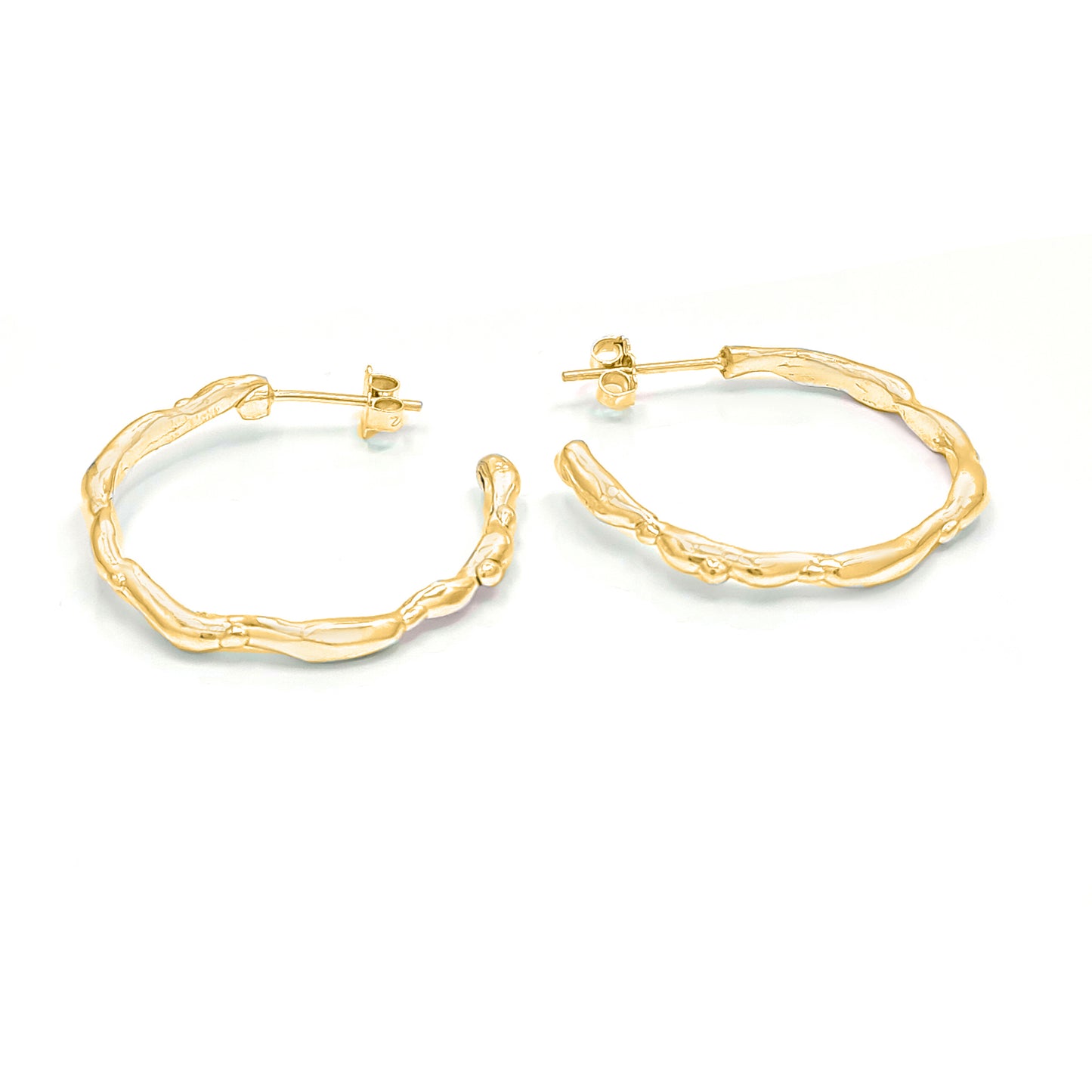 The Hoop 45mm earrings from FR | Art Jewellery are a pair of 18ct gold-plated hoop earrings featuring a textured, organic design. Their unique, uneven surface evokes a natural, twig-like pattern. They are displayed side by side on a white background.