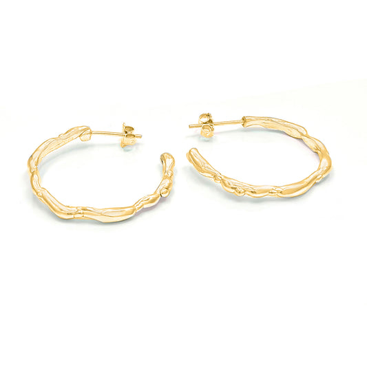 The Hoop 45mm earrings from FR | Art Jewellery are a pair of 18ct gold-plated hoop earrings featuring a textured, organic design. Their unique, uneven surface evokes a natural, twig-like pattern. They are displayed side by side on a white background.