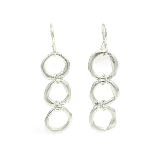 Introducing the "Join Together Earrings" by FR | Art Jewellery: a pair of elegant dangle earrings featuring three interlocking, irregularly shaped silver rings. Handmade with precision, these rings are linked vertically to create a fluid and contemporary design. The earrings also come with simple hook fastenings at the top for easy wear.