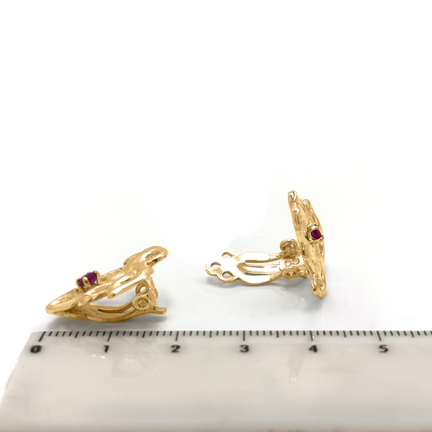 Gold-plated sterling silver maple-shaped clip-on earrings with a ruby gemstone in the centre by Francisca Rendic