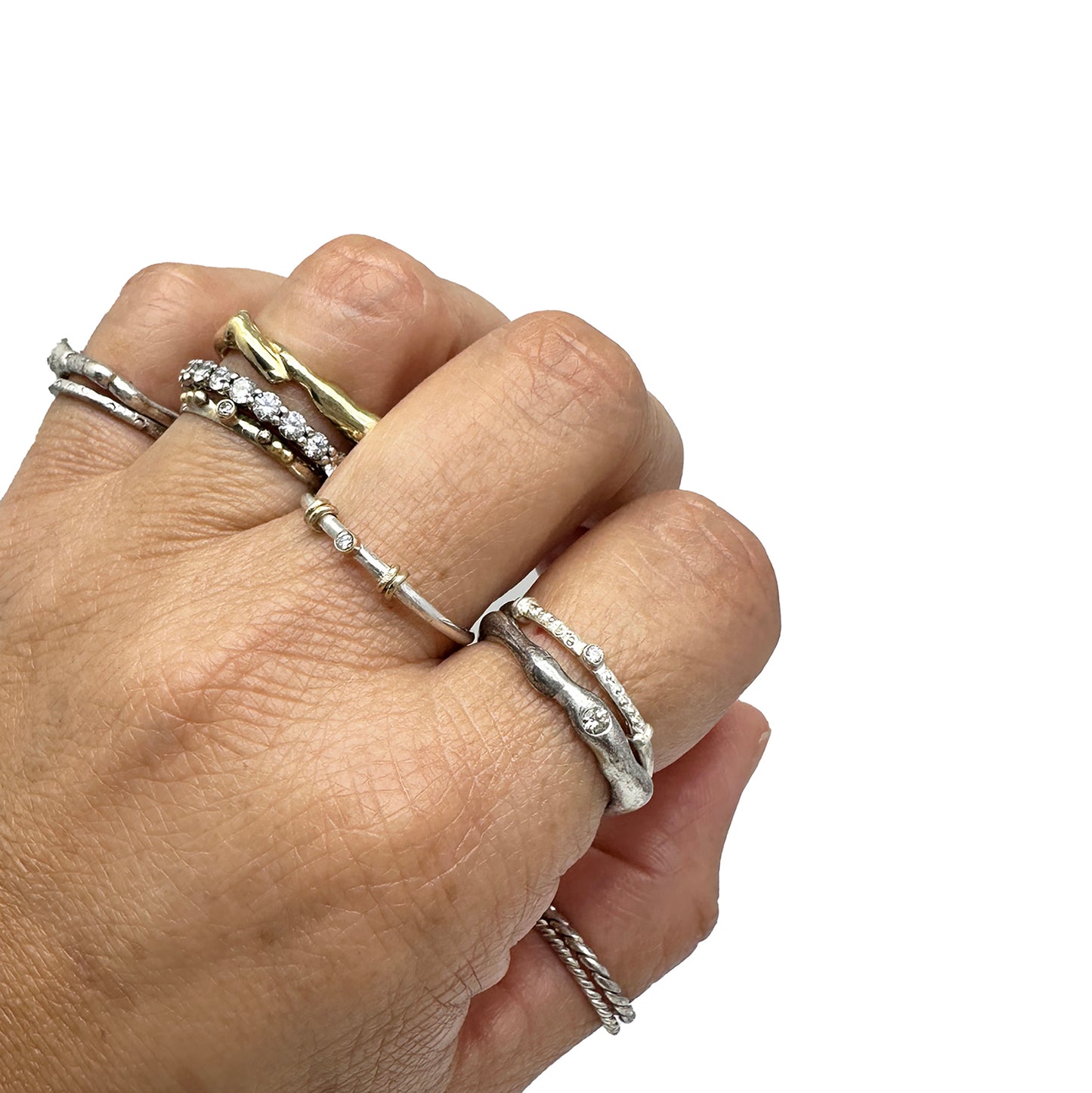 A collection of six Miniature Rings from FR | Art Jewellery is displayed on a white background. Five of the rings are crafted from silver with small gem accents, and one is gold, featuring a slightly larger central stone. Each handmade piece exhibits its own unique design and arrangement of stones.