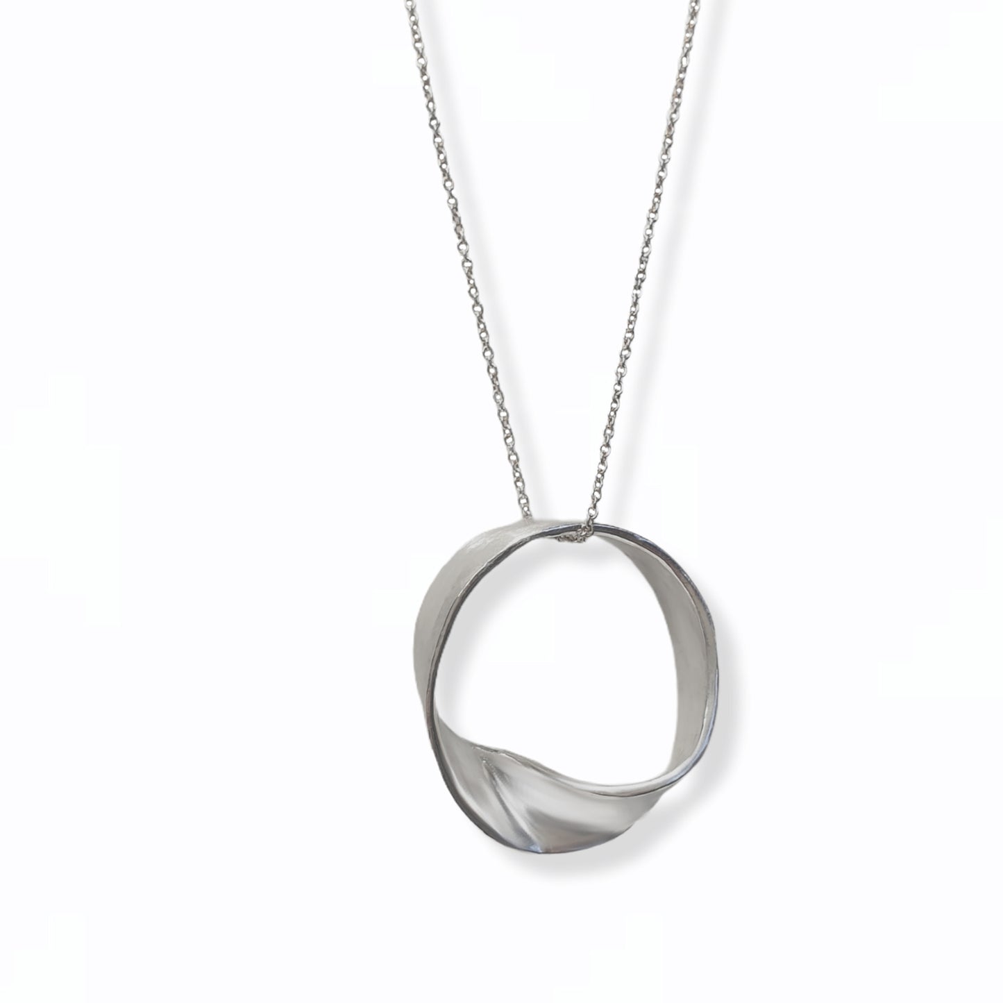 Introducing the MoeBius Band Necklace by FR | Art Jewellery: a minimalist silver necklace showcasing a twisted, flat circular pendant suspended from a delicate silver chain. This piece of handmade jewellery boasts a sleek, modern design with a continuous loop that appears gently twisted. Available for custom-made orders, all set against a plain white background.