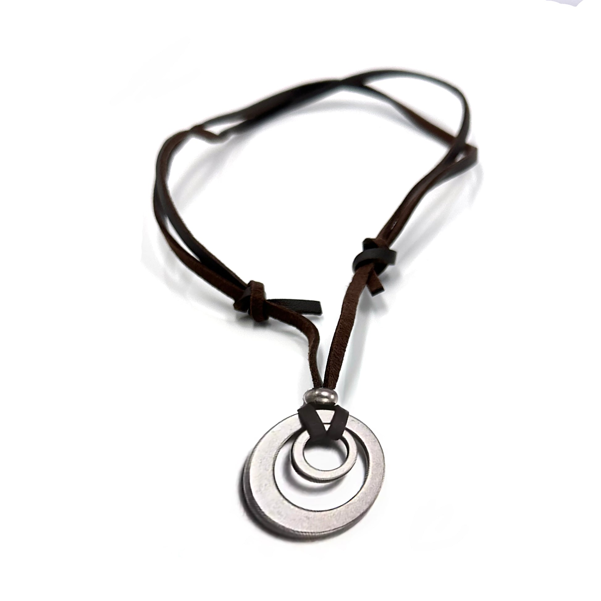 The FR | Art Jewellery Stainless Steel and Leather Circle Necklace by Thamus Design features two linked silver rings on a brown leather cord with knot and bead accents, shown against a white background.