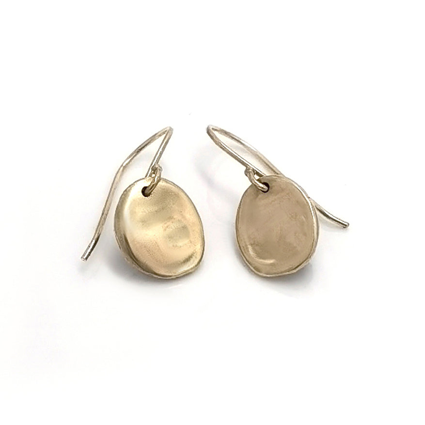 Introducing the New Moon Earrings by FR | Art Jewellery: a pair of minimalist, silver round disc earrings with smooth, slightly irregular surfaces that dangle gracefully from simple hook wire attachments. This handmade jewellery design is sleek and modern, emphasizing clean lines and understated elegance.