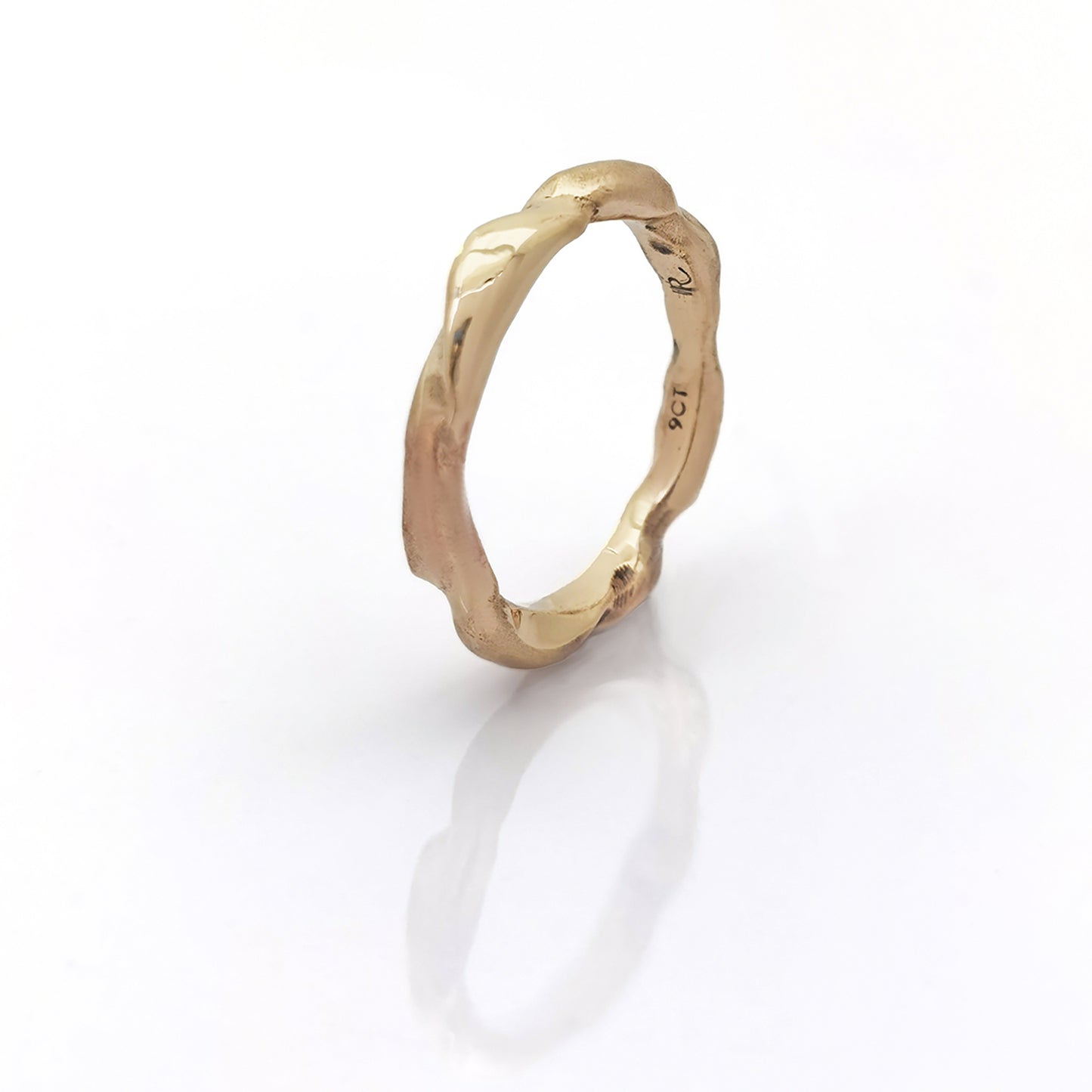 The Ocean Band by FR | Art Jewellery is a gold ring featuring a distinctive wavy texture that wraps around the band. With its polished finish and handcrafted appearance, the ring exudes an organic and artistic vibe. Subtle engravings adorn the inside of the band. This exquisite piece of handmade jewellery is showcased against a white background.
